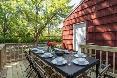 a table on the back porch of a red barn at Spacious 5BR Firepit with Deck Near OSU and More in Columbus