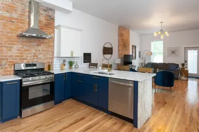 a kitchen with blue cabinets and a brick wall at 2BR Townhome - Free Parking, Minutes to Stadiums in Covington