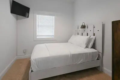 a white bedroom with a bed and a television at Two Condos for 14 Guests, 5 Bedrooms, Free Parking in Covington
