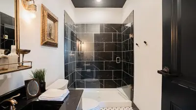 a bathroom with a tub and a shower with black tiles at Pickle Factory Hotel - 2BR Next to Wenzel Distillery in Covington