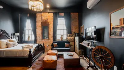 a living room with a bed and a tv and a couch at Pickle Factory Hotel - 2BR Next to Wenzel Distillery in Covington