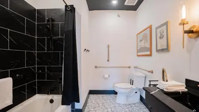 a bathroom with a tub and a toilet and a sink at Pickle Factory Hotel - 2BR Next to Wenzel Distillery in Covington