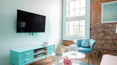 a living room with a tv and a blue chair at Pickle Factory Hotel - 1BR Historic Downtown with Parking in Covington