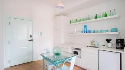 a kitchen with a glass table and white cabinets at Pickle Factory Hotel - 1BR Historic Downtown with Parking in Covington