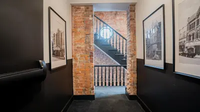 a hallway with pictures on the walls and a staircase at Pickle Factory Hotel - 1BR Historic Downtown with Parking in Covington