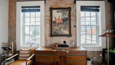 a room with a wooden dresser and two windows at Pickle Factory Hotel - 1BR Close to Stadiums & Bars in Covington