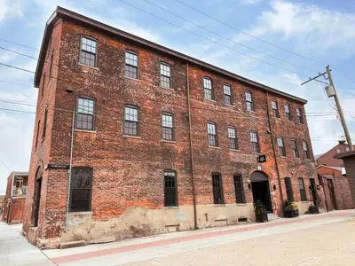 a large brick building on the corner of a street at Pickle Factory Hotel - 1BR Close to Stadiums & Bars in Covington