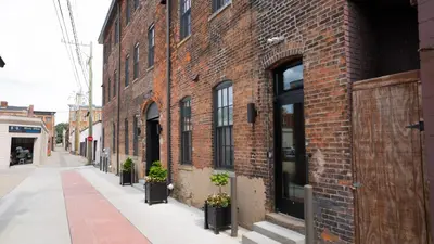 a brick building with potted plants on a street at Pickle Factory Hotel - 1BR Close to Stadiums & Bars in Covington
