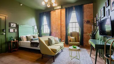 a living room with a couch and a tv at Pickle Factory Hotel - 2BR Near Stadiums & Downtown in Covington