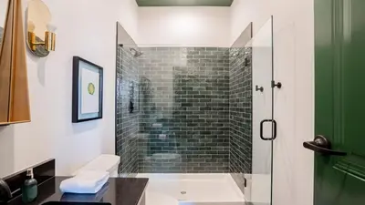 a bathroom with a shower with a glass door at Pickle Factory Hotel - 2BR Near Stadiums & Downtown in Covington