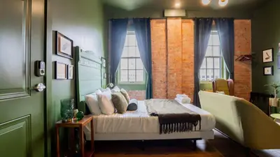 a bedroom with a bed in a green room at Pickle Factory Hotel - 2BR Near Stadiums & Downtown in Covington