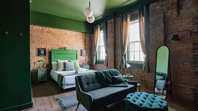a green bedroom with a bed and a chair at Pickle Factory Hotel - 2BR Near Stadiums & Downtown in Covington