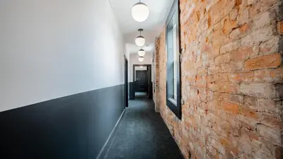 a hallway with a red brick wall and lights at Pickle Factory Hotel - 1BR Near Bars & Restaurants in Covington