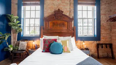a bedroom with a large bed with a wooden headboard at Pickle Factory Hotel - 1BR Beside New Distillery! in Covington