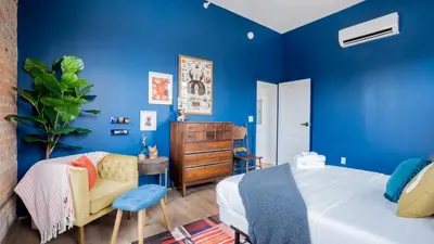 a blue bedroom with a bed and a chair at Pickle Factory Hotel - 1BR Beside New Distillery! in Covington
