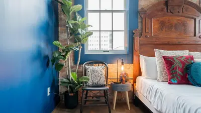 a bedroom with blue walls and a bed with a wooden headboard at Pickle Factory Hotel - 1BR Beside New Distillery! in Covington