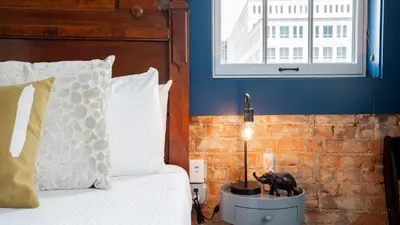 a bedroom with a bed and a blue wall at Pickle Factory Hotel - 1BR Beside New Distillery! in Covington