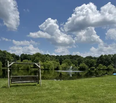 a park bench sitting in the grass near a lake at Fisherman’s Dream in McArthur