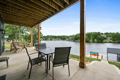 a patio with a table and chairs and a view of a river at Lakefront Home with Dock - Hot tub - 7 miles to Ark in Williamstown