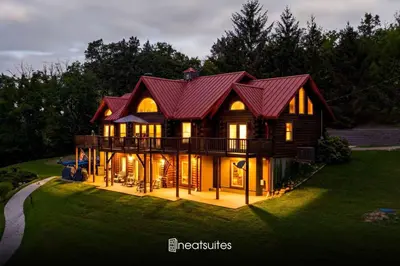 a large house with a red roof on a green field at Lakeside Log Home, Private Dock, Near Ark! in Dry Ridge