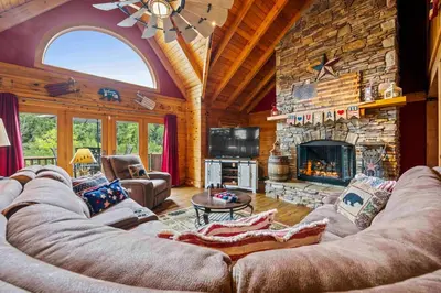 a large living room with a large stone fireplace at Lakeside Log Home, Private Dock, Near Ark! in Dry Ridge