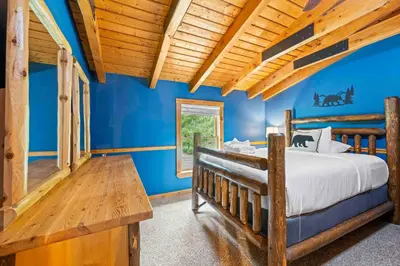 a bedroom with a wooden bed and blue walls at Lakeside Log Home, Private Dock, Near Ark! in Dry Ridge