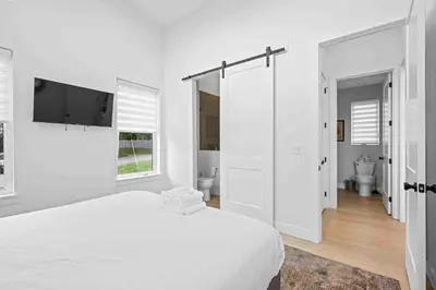 a white bedroom with a bed and a flat screen tv at Hot Tub, 3BR for 10, Near Ark, Private Parking in Dry Ridge
