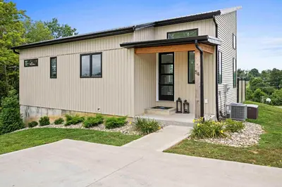 a small house with a porch on a lawn at 3 Homes, 3 Hot Tubs, 10BR, 10 Bath, Near Ark! in Dry Ridge