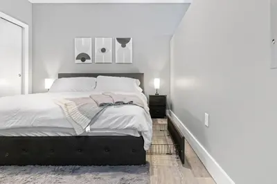 a white bedroom with a large bed with white walls at Modern DT Stay, King Bed, Parking Available in Cleveland