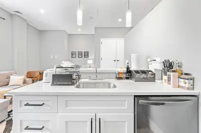 a white kitchen with a sink and a couch at Modern DT Stay, King Bed, Parking Available in Cleveland
