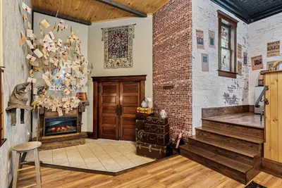a living room with a fireplace and a staircase at School of Sorcery in Brinkhaven