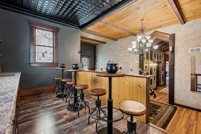 a bar with stools in a room with wooden walls at School of Sorcery in Brinkhaven