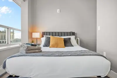 a bedroom with a large white bed with a window at 1BR Retreat, 2 Smart TVs, WiFi & Free Parking in Cleveland