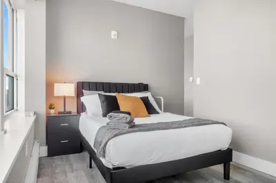 a bedroom with a bed with white sheets and orange pillows at 1BR Retreat, 2 Smart TVs, WiFi & Free Parking in Cleveland