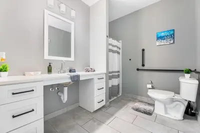 a white bathroom with a toilet and a sink at 1BR Retreat, 2 Smart TVs, WiFi & Free Parking in Cleveland