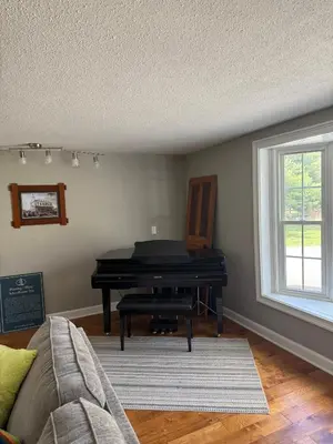 a living room with a piano and a couch at Old Orchard