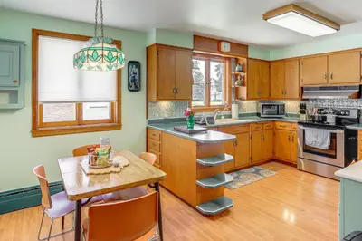 a kitchen with wooden cabinets and a wooden table at Less Than 1 Mi to Dtwn Tiffin Home with Outdoor Space! in Tiffin
