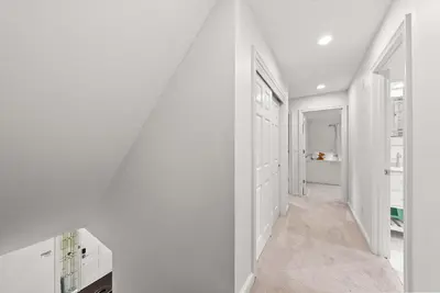 a hallway with white walls and a white staircase at The Gahanna Grand in Columbus