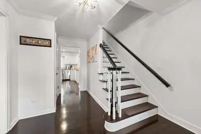 a staircase in a home with white walls and a chandelier at The Gahanna Grand in Columbus