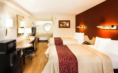 a hotel room with two beds and a desk at Red Roof Inn Parkersburg in Parkersburg