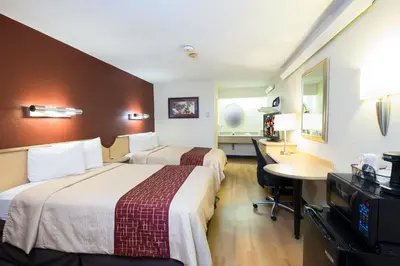 a hotel room with two beds and a desk at Red Roof Inn Parkersburg in Parkersburg