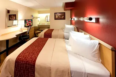 a hotel room with two beds and a desk at Red Roof Inn Parkersburg in Parkersburg