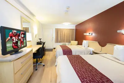 a hotel room with two beds and a flat screen tv at Red Roof Inn Parkersburg in Parkersburg