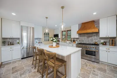 a kitchen with white cabinets and a kitchen island with chairs at Bellawood Farmhouse in Canal Winchester