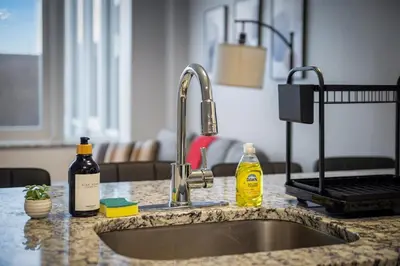 a kitchen counter with a sink and two bottles of alcohol at King Bed Comfort, Bidet, Fast Wi-Fi, Parking in Cleveland