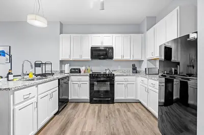 a large kitchen with white cabinets and black appliances at King Bed Comfort, Bidet, Fast Wi-Fi, Parking in Cleveland