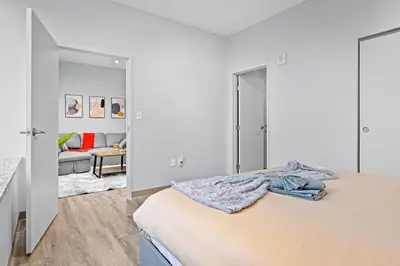 a white bedroom with a bed and a living room at King Bed Comfort, Bidet, Fast Wi-Fi, Parking in Cleveland