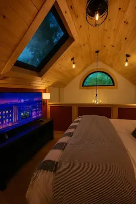 a bedroom with a bed and a large screen tv at Lux Tiny House with Waterfront, Kayaks, Hot Tub, Arcade in Rockbridge