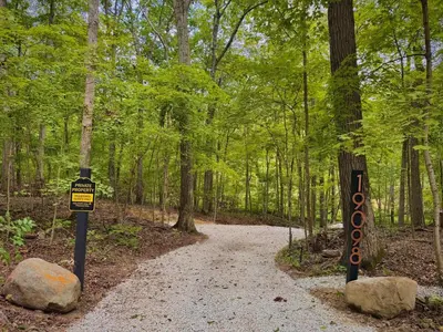 a trail in the woods with a sign on it at Lux Tiny House with Waterfront, Kayaks, Hot Tub, Arcade in Rockbridge