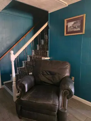 a leather couch in a living room with a staircase at La Casa delle Pesche in Georgetown